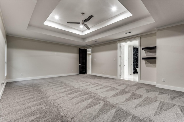 interior space with a tray ceiling, carpet flooring, visible vents, and a ceiling fan