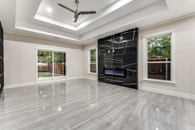 unfurnished living room with baseboards, a raised ceiling, and a tile fireplace