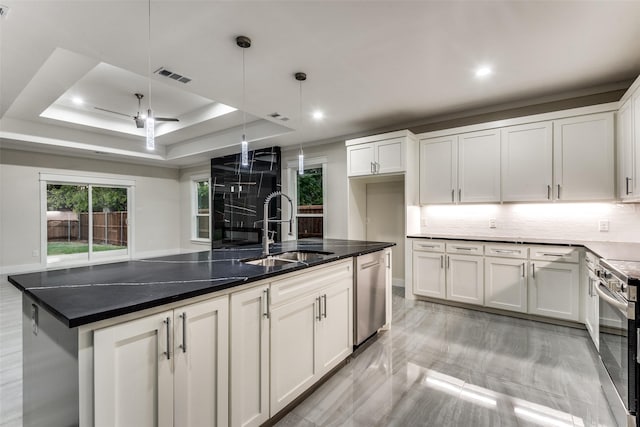 kitchen featuring a tray ceiling, stainless steel appliances, visible vents, white cabinets, and a sink