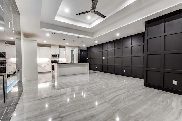 interior space with visible vents, ceiling fan, a tray ceiling, a decorative wall, and recessed lighting