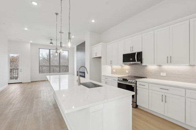 kitchen featuring a sink, white cabinets, appliances with stainless steel finishes, backsplash, and light wood finished floors