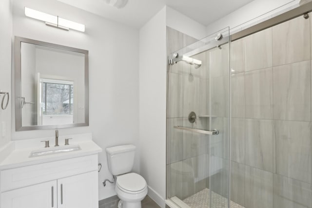 bathroom with vanity, a shower stall, toilet, and baseboards