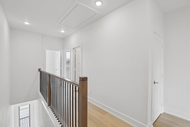 corridor with light wood finished floors, baseboards, and an upstairs landing