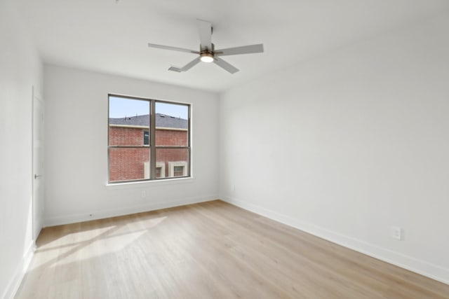 empty room featuring a ceiling fan, baseboards, and light wood finished floors