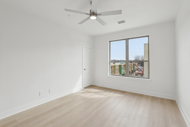 unfurnished room with baseboards, light wood-type flooring, visible vents, and a ceiling fan