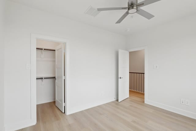 unfurnished bedroom featuring light wood finished floors, baseboards, and a walk in closet