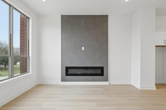 unfurnished living room with a large fireplace, baseboards, light wood finished floors, and recessed lighting