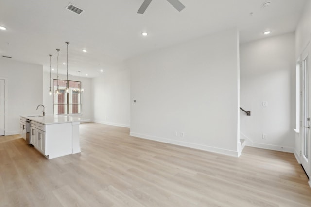 unfurnished living room with light wood-type flooring, a sink, visible vents, and recessed lighting