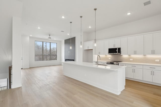 kitchen featuring tasteful backsplash, visible vents, appliances with stainless steel finishes, white cabinets, and a sink