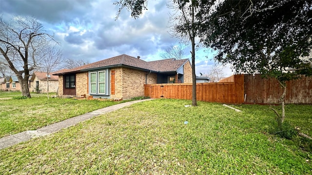 view of property exterior with a shingled roof, brick siding, fence, and a lawn