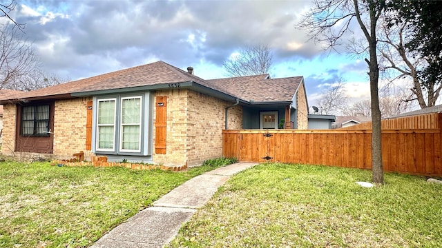 view of property exterior with a yard, brick siding, fence, and a shingled roof