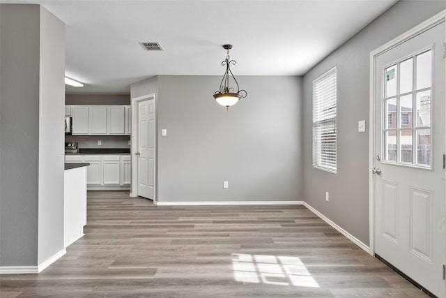 unfurnished dining area with baseboards, visible vents, and light wood-type flooring