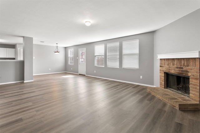 unfurnished living room with a fireplace, baseboards, and wood finished floors