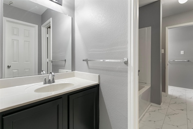 bathroom featuring vanity, a tub, marble finish floor, and baseboards