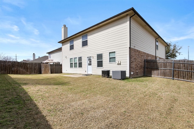 rear view of property featuring a yard, a fenced backyard, brick siding, and central AC