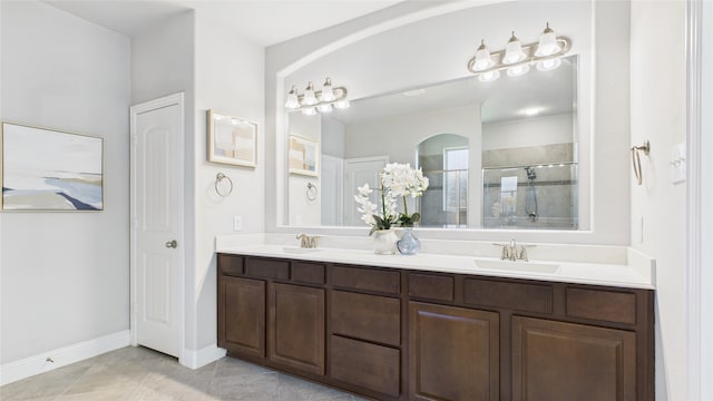 full bath featuring a sink, baseboards, tile patterned floors, double vanity, and a stall shower