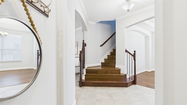 stairs featuring arched walkways, an inviting chandelier, ornamental molding, tile patterned flooring, and baseboards