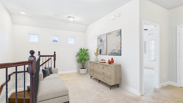 living area with an upstairs landing, baseboards, visible vents, and light colored carpet