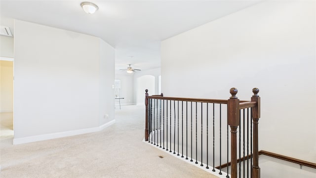 corridor featuring arched walkways, carpet, an upstairs landing, and baseboards