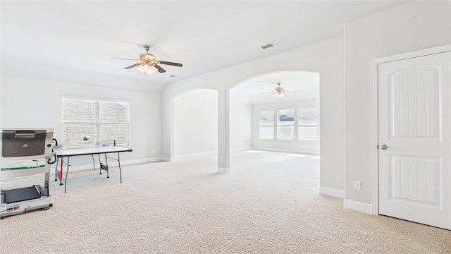 interior space with carpet floors, arched walkways, visible vents, and a ceiling fan