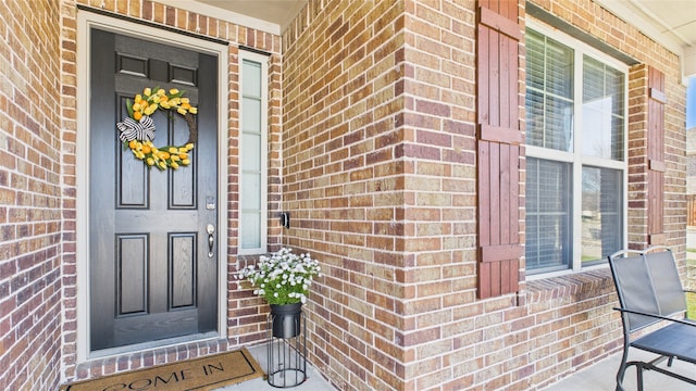 entrance to property with a porch and brick siding