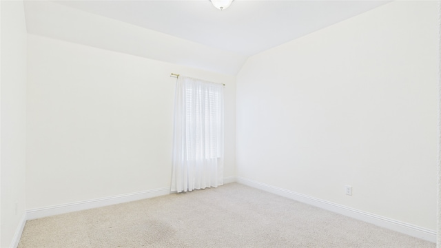 empty room with lofted ceiling, baseboards, and light colored carpet