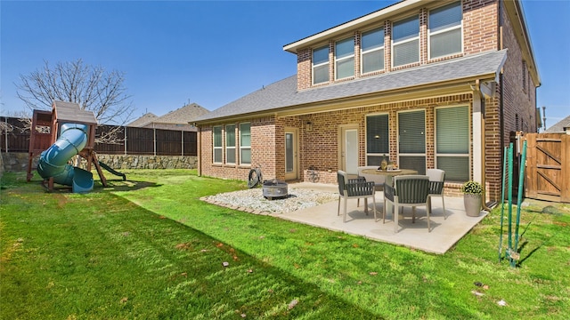 back of house featuring a lawn, a patio, a fenced backyard, a playground, and brick siding