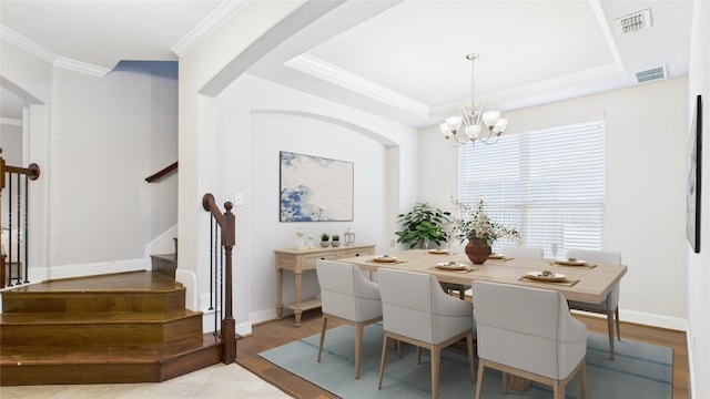 dining space featuring wood finished floors, baseboards, stairs, a raised ceiling, and crown molding