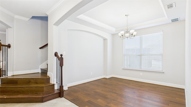 stairs with wood finished floors, visible vents, baseboards, ornamental molding, and a raised ceiling