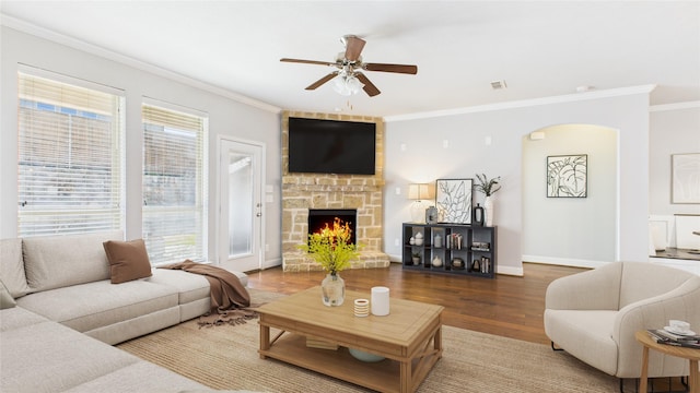 living room with crown molding, a fireplace, ceiling fan, wood finished floors, and baseboards