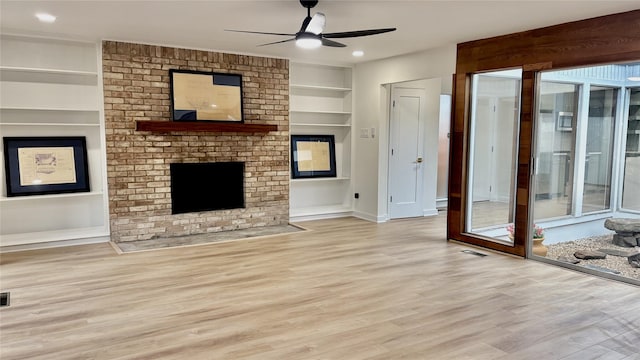 unfurnished living room with built in shelves, a wealth of natural light, visible vents, ceiling fan, and wood finished floors