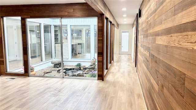 corridor featuring wood walls, a barn door, wood finished floors, and recessed lighting