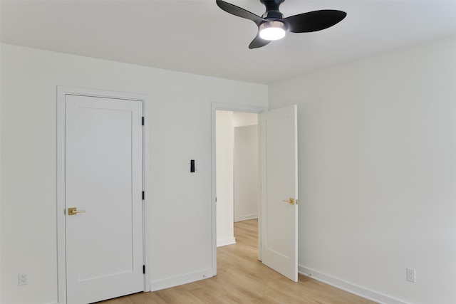 unfurnished bedroom with light wood-type flooring, a ceiling fan, and baseboards