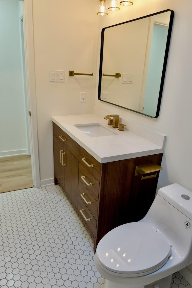 half bathroom featuring tile patterned flooring, vanity, and toilet