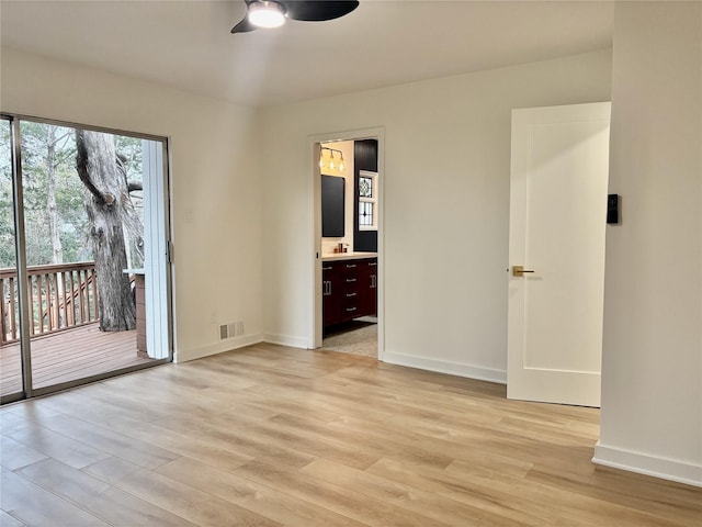 empty room with a ceiling fan, light wood-type flooring, visible vents, and baseboards