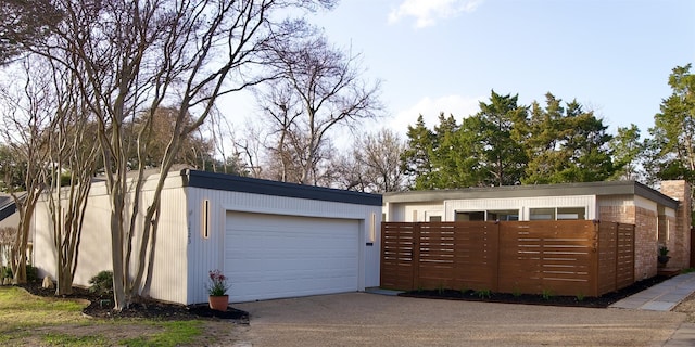 view of front facade featuring brick siding, a fenced front yard, and a detached garage