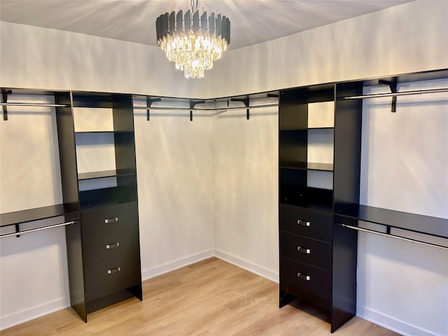 spacious closet featuring light wood-type flooring and a notable chandelier