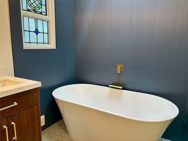 bathroom featuring tile walls, a freestanding tub, and vanity