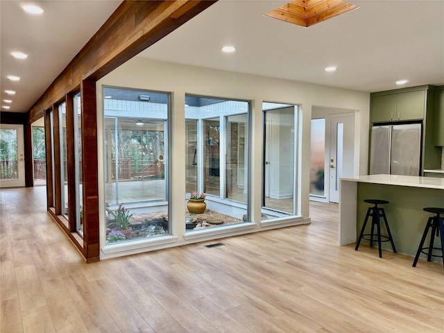 interior space featuring light wood-style floors, a healthy amount of sunlight, and beamed ceiling