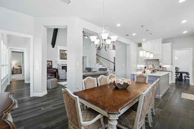 dining area featuring dark wood-type flooring, a fireplace, recessed lighting, and a notable chandelier