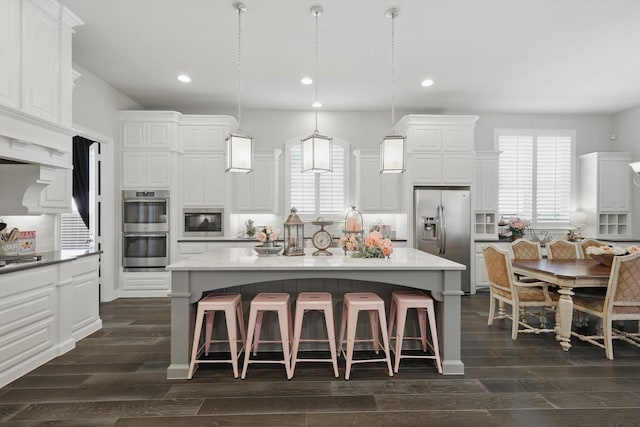 kitchen with dark wood-style flooring, appliances with stainless steel finishes, a healthy amount of sunlight, and tasteful backsplash