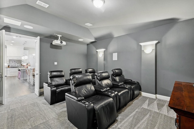 cinema featuring vaulted ceiling, light carpet, visible vents, and baseboards