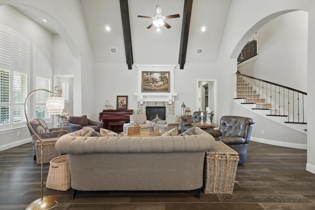 living room with high vaulted ceiling, dark wood finished floors, a stone fireplace, and baseboards