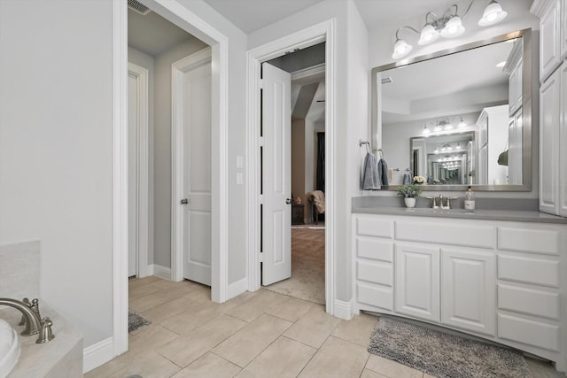 bathroom with visible vents, a washtub, vanity, and baseboards