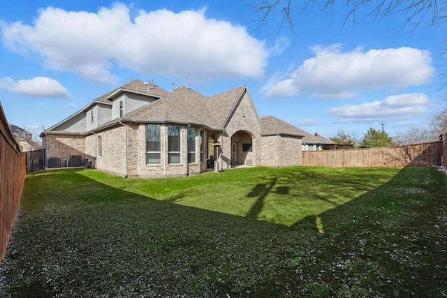 back of property with brick siding, a lawn, central AC unit, and a fenced backyard