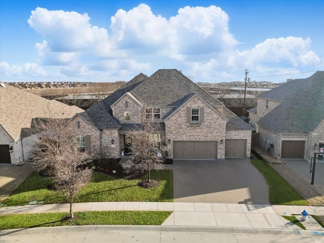 french provincial home with brick siding, a shingled roof, an attached garage, decorative driveway, and a front yard