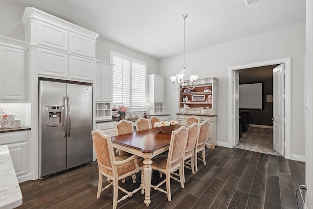 dining room with dark wood finished floors, a notable chandelier, and baseboards