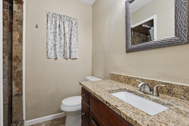 full bath featuring a textured wall, a tile shower, vanity, and toilet