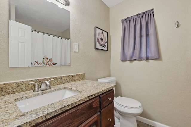 full bath with a textured wall, a shower with shower curtain, toilet, vanity, and baseboards