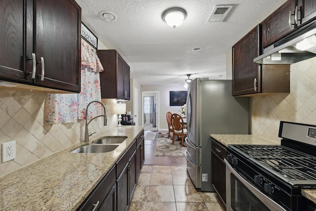 kitchen featuring visible vents, a ceiling fan, stainless steel range with gas stovetop, a sink, and under cabinet range hood